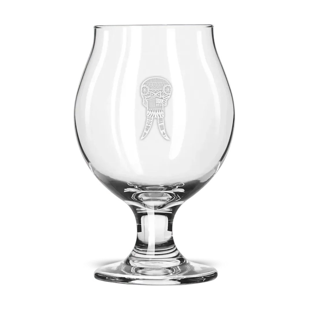 Clear snifter glass with etched decorative walrus head design on front, isolated background