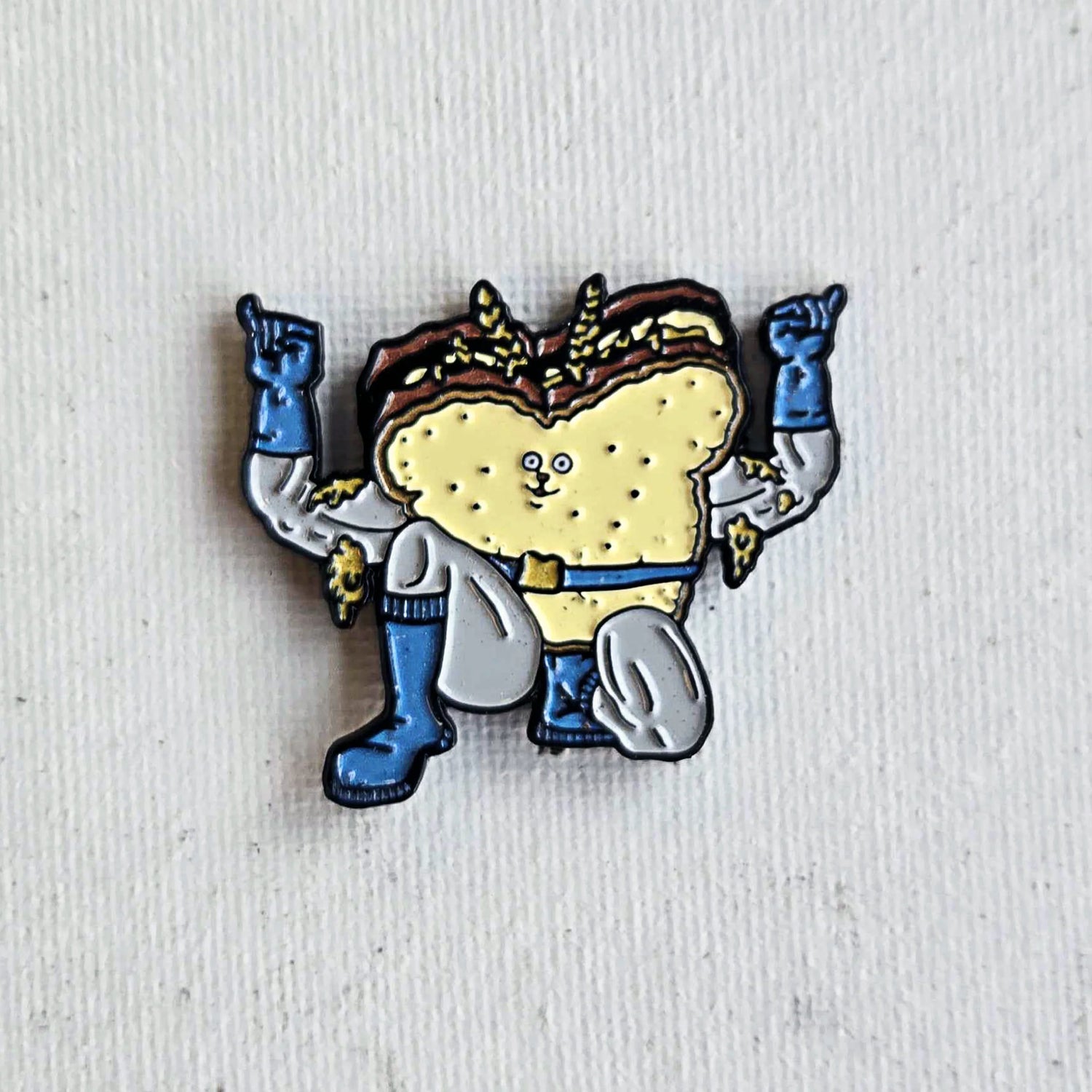 Superhero peanut butter and jelly sandwich enamel pin on white fabric background