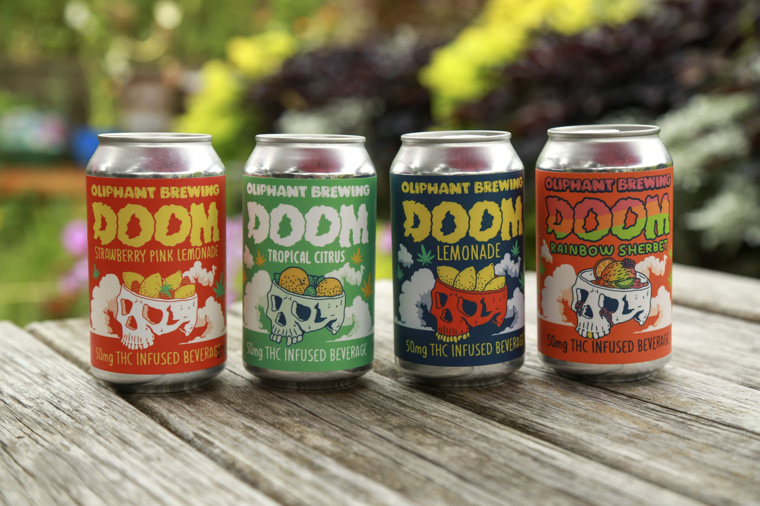 Oliphant Brewing DOOM THC beverages in cans on wooden table outdoors, four flavors visible