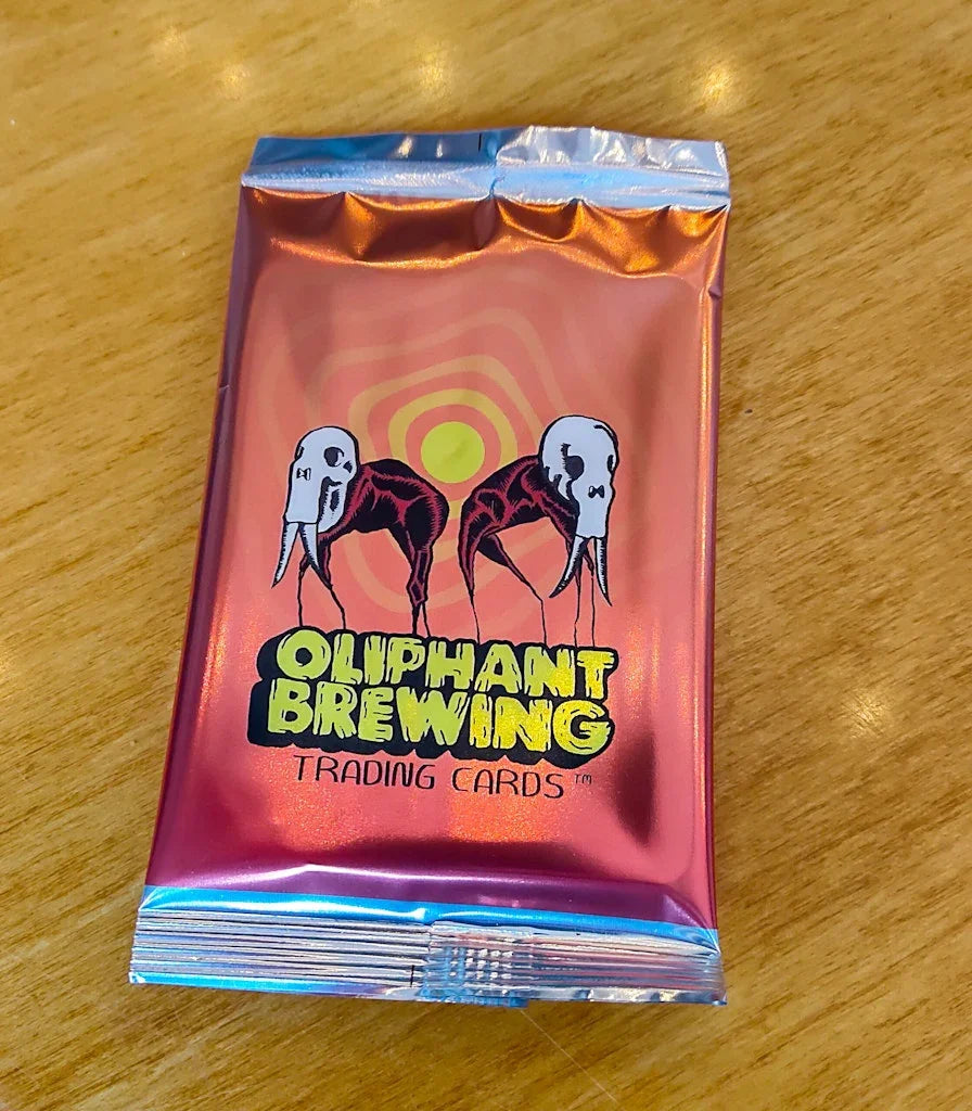 Oliphant Brewing trading cards metallic pack on wooden table, surreal elephant skull design