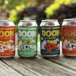 Oliphant Brewing DOOM THC infused beverage cans in four flavors on wooden table outdoors